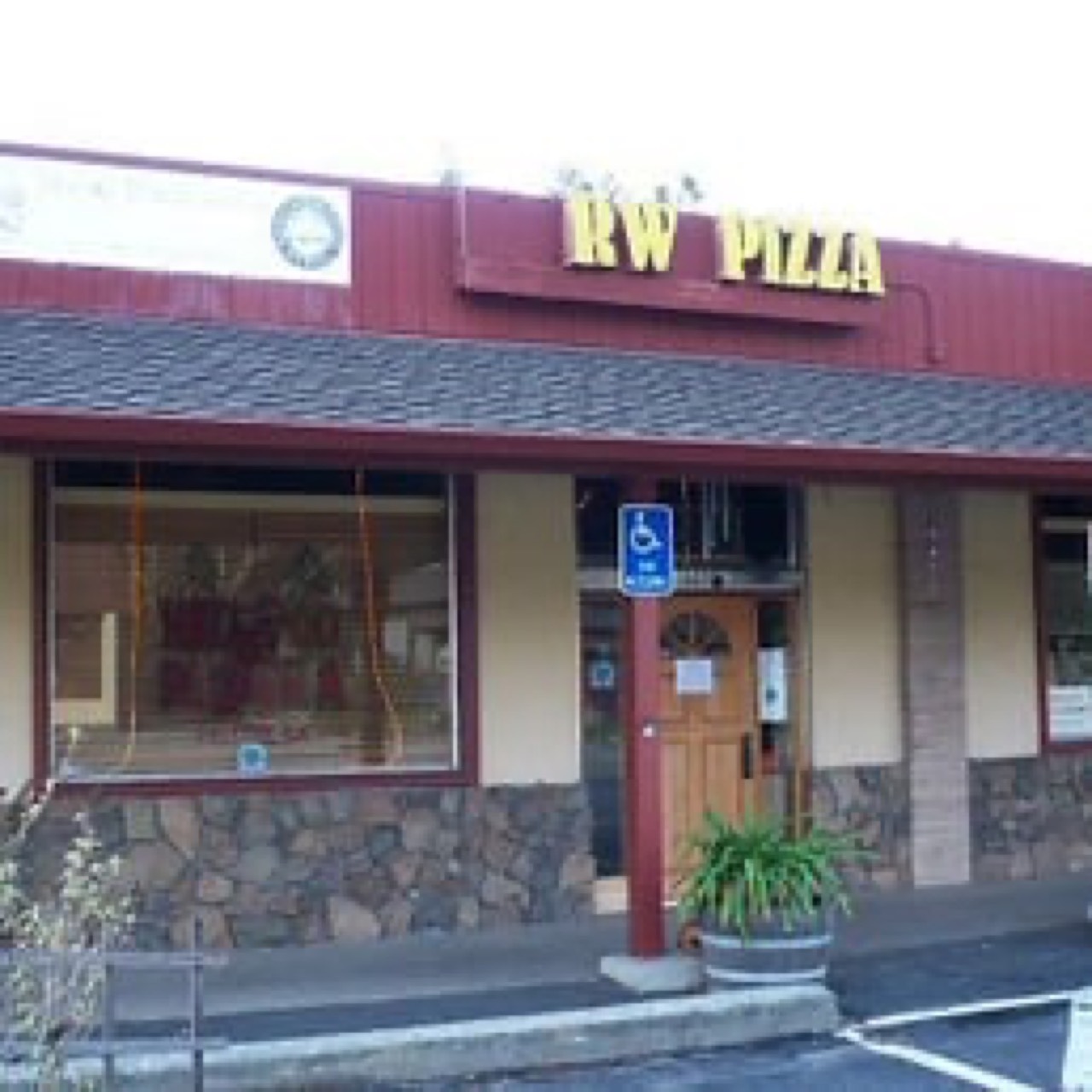 Redwood Pizzeria storefront with RW Pizza sign and stone facade, daytime.