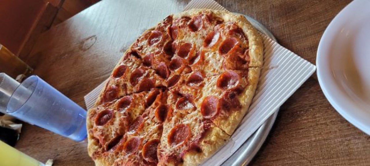 Pepperoni pizza cut into slices on a metal pan, top-down view.