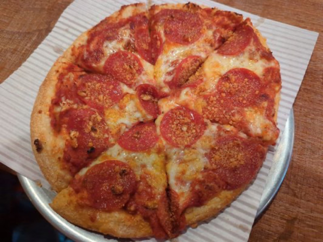 Pepperoni and sausage crumble pizza on a metal pan with wax paper.