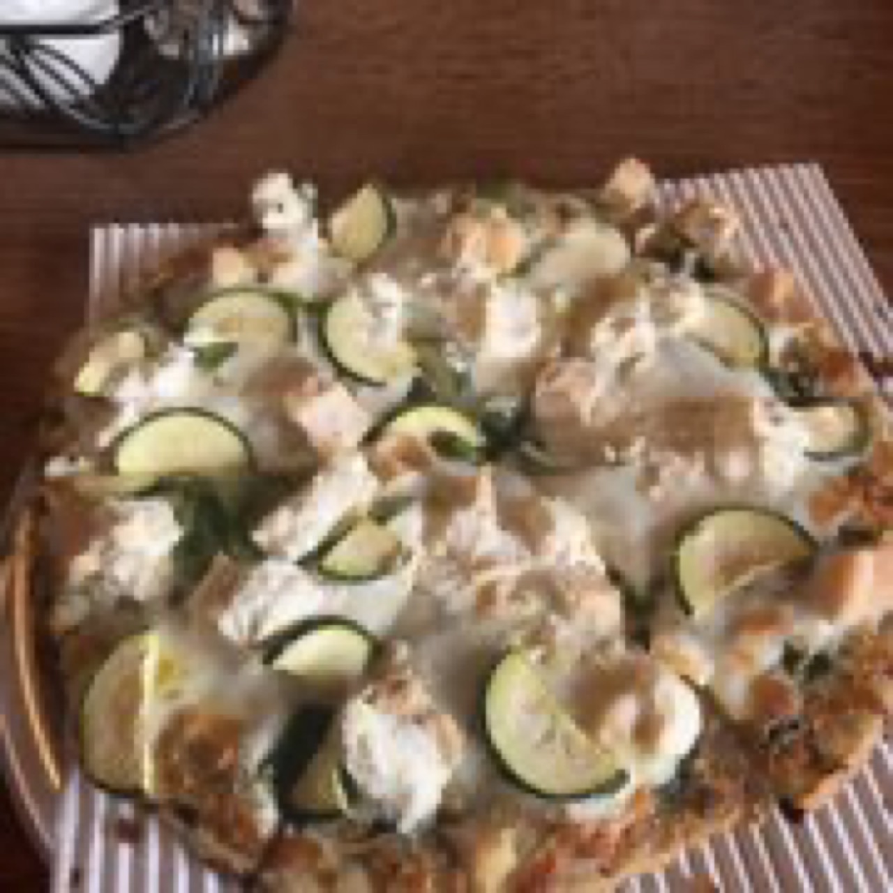 White pizza topped with zucchini slices and ricotta on a round pan.