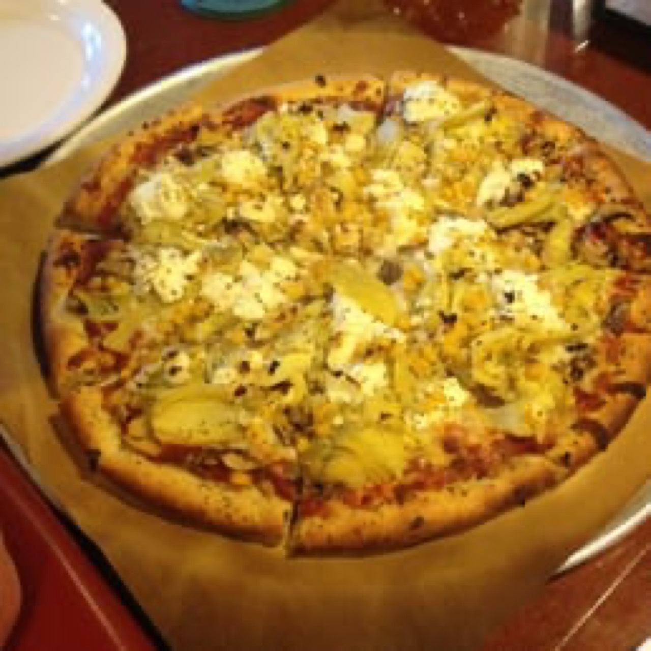 Artichoke and ricotta pizza with herbs on a metal pan, top-down.